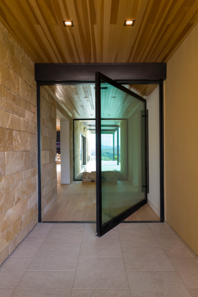 Foto di una porta d'ingresso minimalista con pareti beige, pavimento in cemento, una porta a pivot, una porta in vetro e soffitto in legno