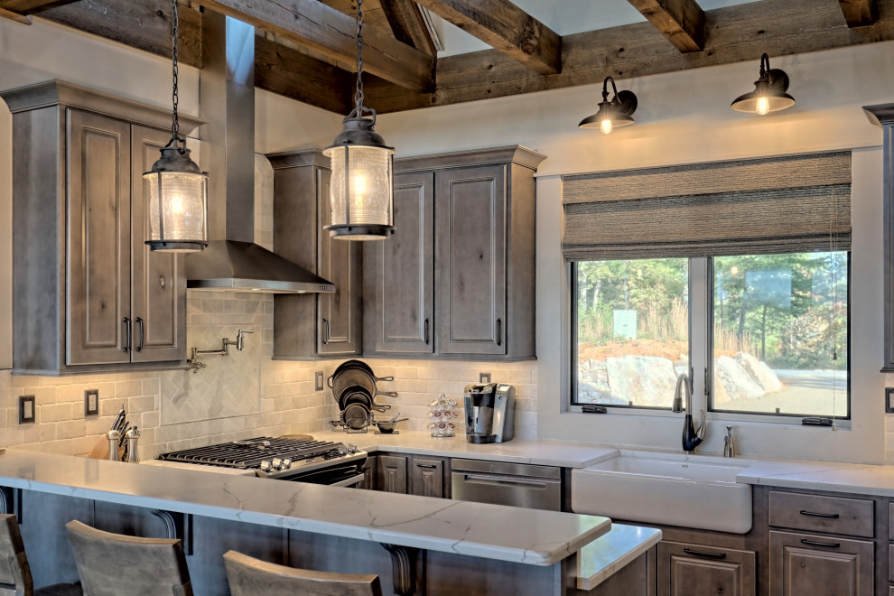 This is an example of a small country u-shaped open plan kitchen in Atlanta with a farmhouse sink, raised-panel cabinets, light wood cabinets, quartz benchtops, white splashback, travertine splashback, stainless steel appliances, a peninsula, brown floor and white benchtop.