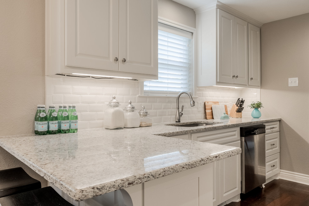 Inspiration for a mid-sized traditional galley separate kitchen in Dallas with an undermount sink, raised-panel cabinets, white cabinets, granite benchtops, white splashback, subway tile splashback, stainless steel appliances, medium hardwood floors and a peninsula.