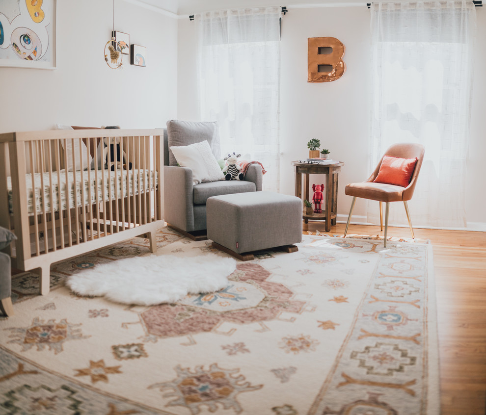 This is an example of a mid-sized eclectic gender-neutral nursery in Los Angeles with white walls and medium hardwood floors.