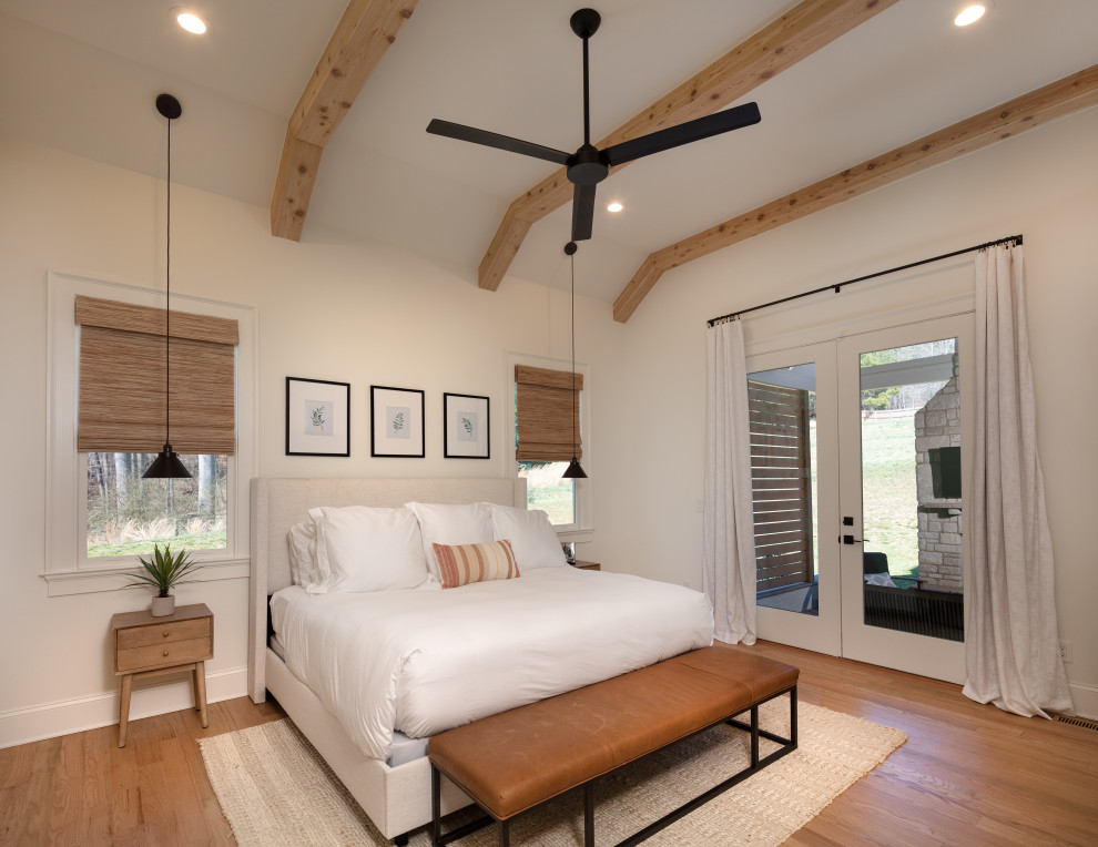 Imagen de dormitorio principal, blanco y blanco y madera de estilo de casa de campo de tamaño medio con paredes blancas, suelo de madera clara, suelo marrón y vigas vistas