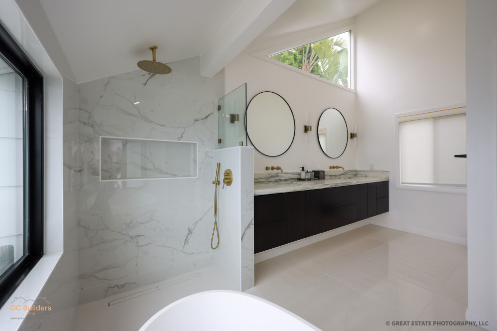 Photo of a large modern master bathroom in Orange County with flat-panel cabinets, black cabinets, a freestanding tub, a curbless shower, a one-piece toilet, multi-coloured tile, white walls, porcelain floors, a drop-in sink, marble benchtops, white floor, an open shower, white benchtops, a niche, a double vanity, a floating vanity and vaulted.