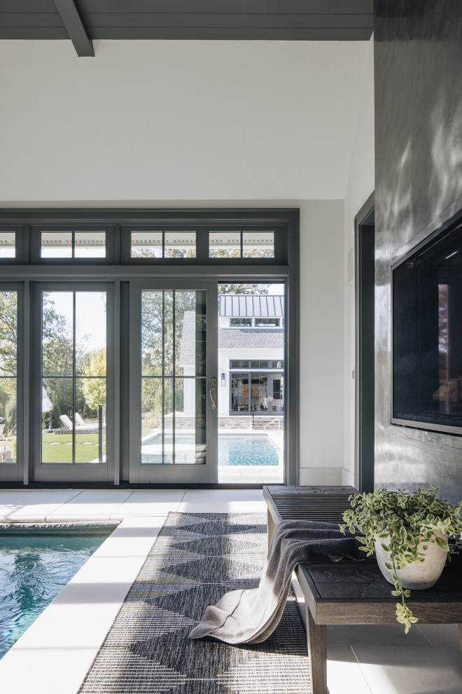 Стильный дизайн: большой прямоугольный бассейн в доме в стиле неоклассика (современная классика) с мощением тротуарной плиткой - последний тренд