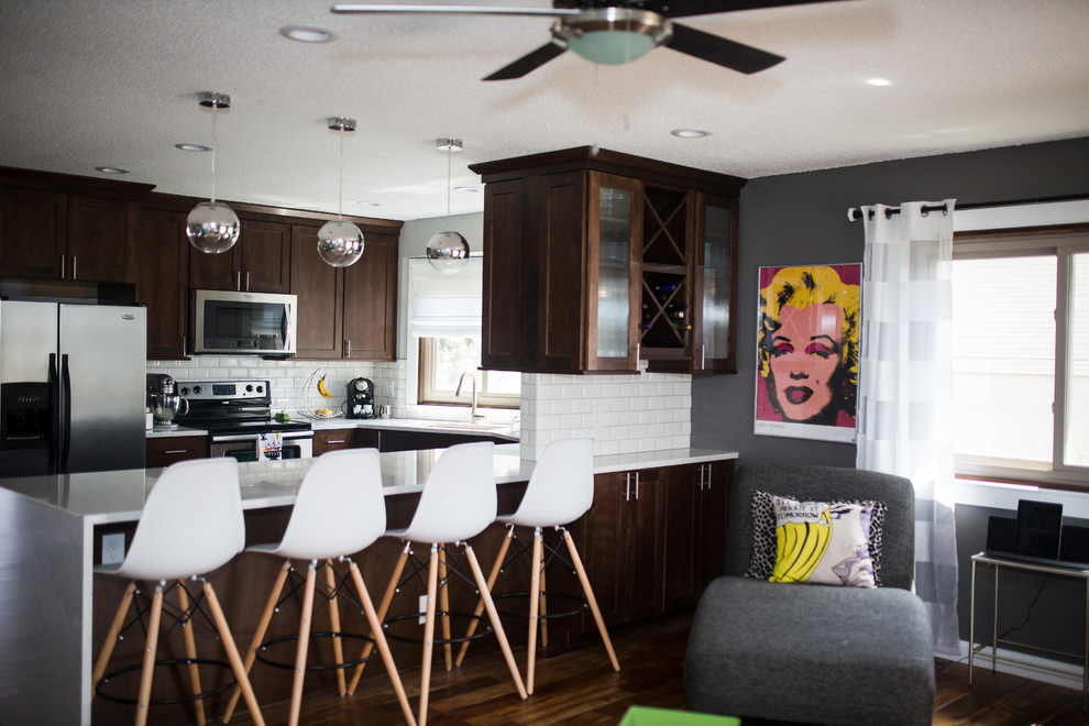 Inspiration for a mid-sized transitional u-shaped dark wood floor and brown floor enclosed kitchen remodel in Omaha with shaker cabinets, dark wood cabinets, quartz countertops, white backsplash, subway tile backsplash, stainless steel appliances, a peninsula and an undermount sink
