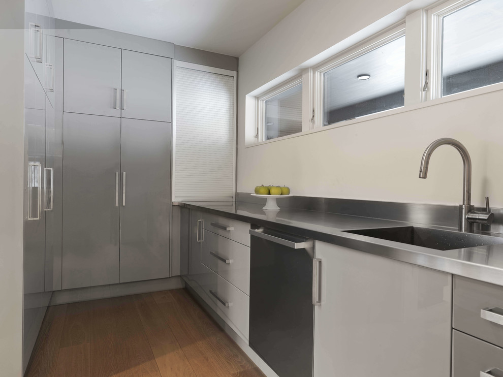 Inspiration for a small modern l-shaped separate kitchen in Burlington with an undermount sink, flat-panel cabinets, grey cabinets, stainless steel benchtops, stainless steel appliances, light hardwood floors, no island and beige floor.
