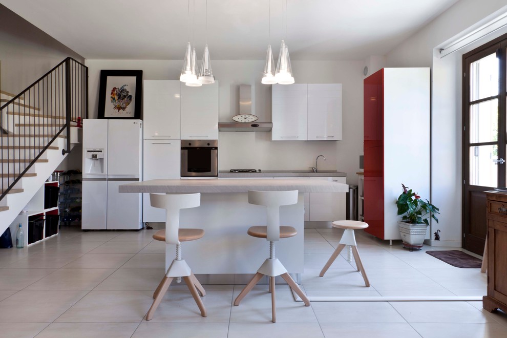 Photo of a mid-sized contemporary single-wall eat-in kitchen in Milan with flat-panel cabinets, white cabinets, concrete benchtops and stainless steel appliances.