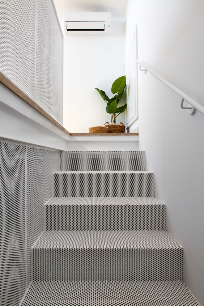 This is an example of a large mediterranean metal straight staircase in Barcelona with metal risers, metal railing and brick walls.