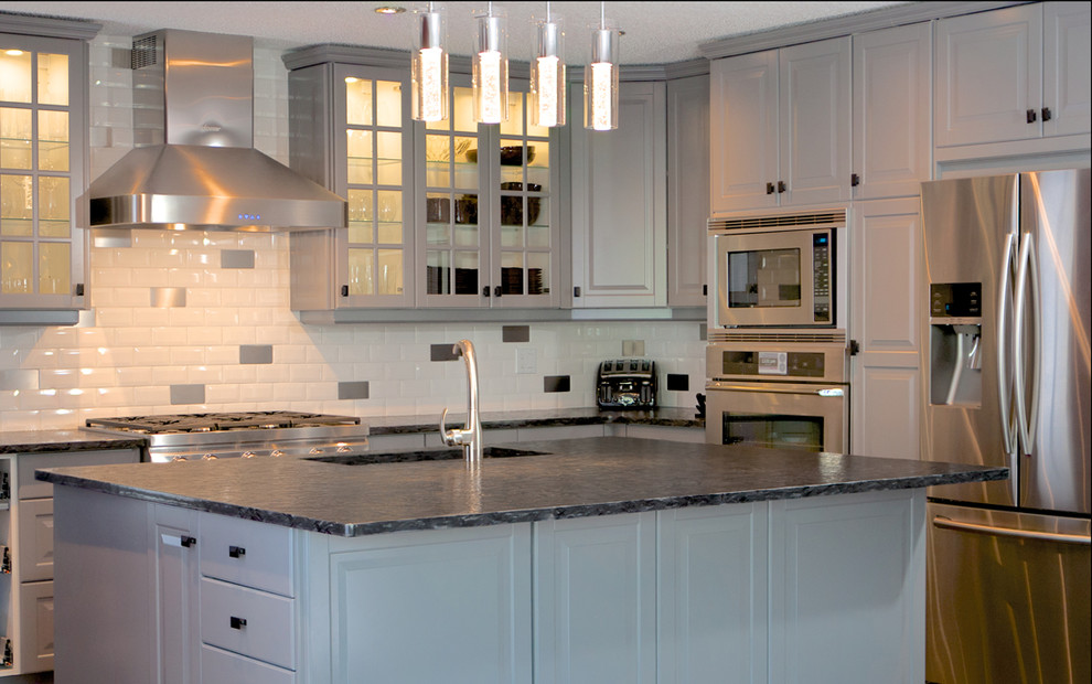 Inspiration for a mid-sized contemporary l-shaped eat-in kitchen in Edmonton with an undermount sink, raised-panel cabinets, white cabinets, zinc benchtops, white splashback, ceramic splashback, stainless steel appliances, with island and dark hardwood floors.