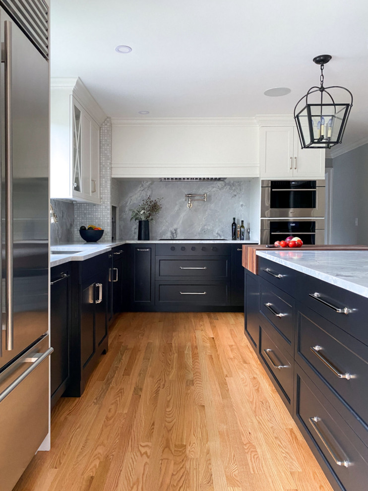 This is an example of a classic kitchen in Boston with a submerged sink, shaker cabinets, black cabinets, quartz worktops, grey splashback, stainless steel appliances, medium hardwood flooring, an island and grey worktops.