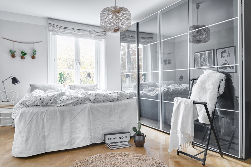 ストックホルムにある中くらいな北欧スタイルのおしゃれな主寝室 (白い壁、淡色無垢フローリング)