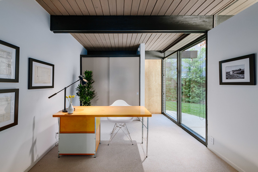This is an example of a mid-sized midcentury home office in Los Angeles with white walls, a freestanding desk, carpet and beige floor.