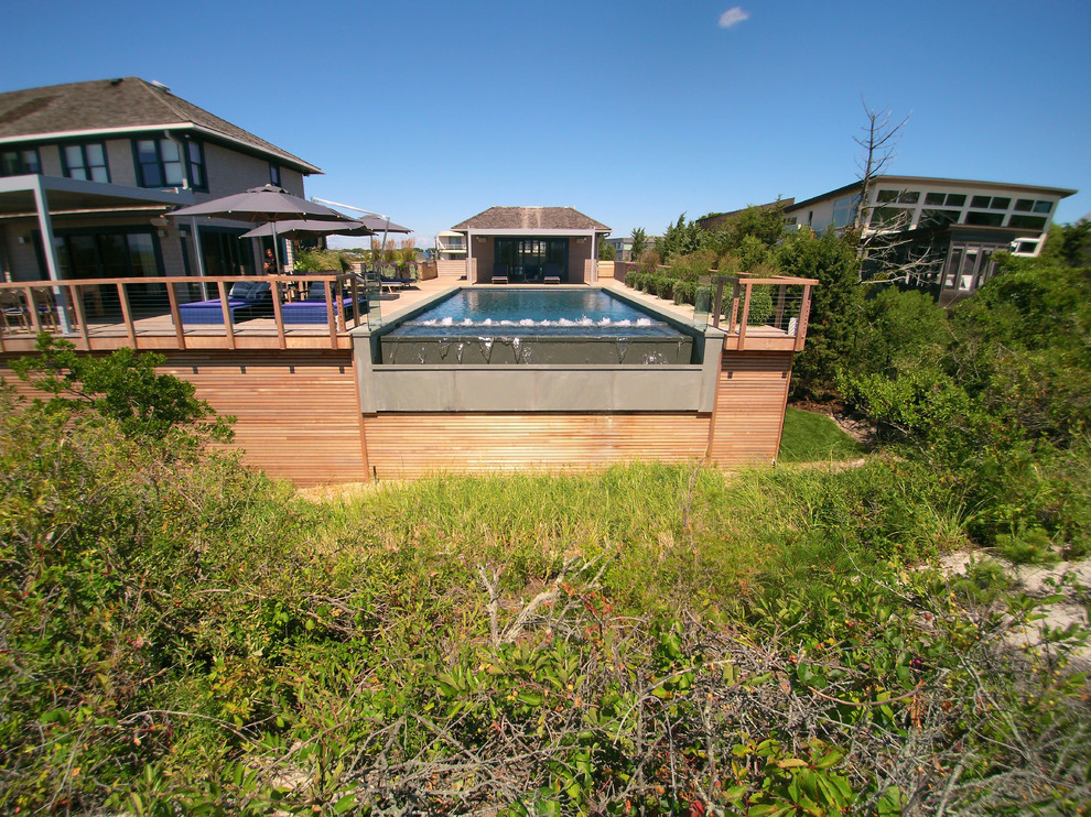 Photo of a contemporary side yard rectangular infinity pool in New York with a hot tub and decking.