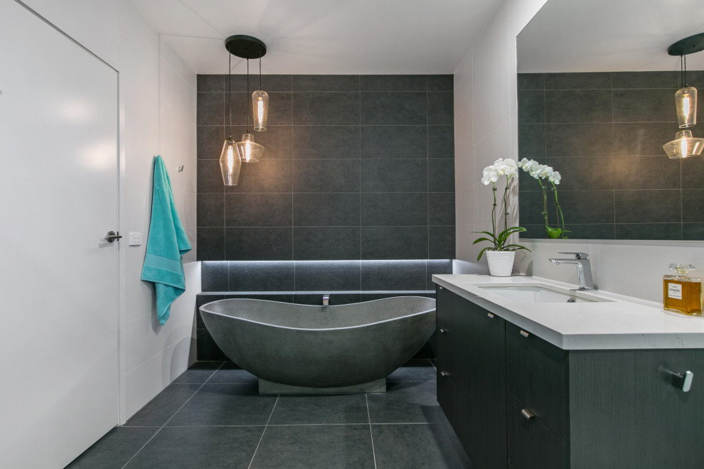 Inspiration for a contemporary bathroom in Other with flat-panel cabinets, grey cabinets, a freestanding tub, gray tile, an undermount sink, grey floor and white benchtops.