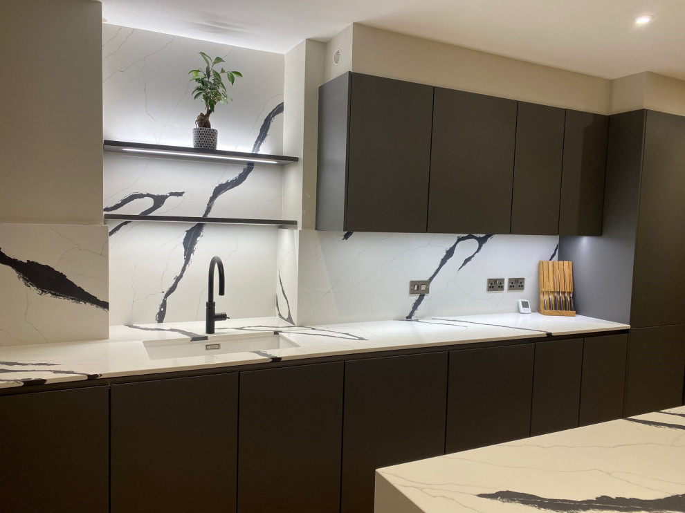 Inredning av ett modernt stort flerfärgad flerfärgat kök, med en undermonterad diskho, luckor med profilerade fronter, grå skåp, bänkskiva i kvartsit, flerfärgad stänkskydd, svarta vitvaror, ljust trägolv, en köksö och brunt golv