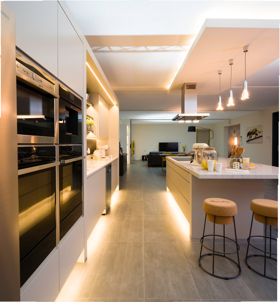 Photo of a large contemporary single-wall kitchen in Dublin with marble benchtops, with island and white benchtop.
