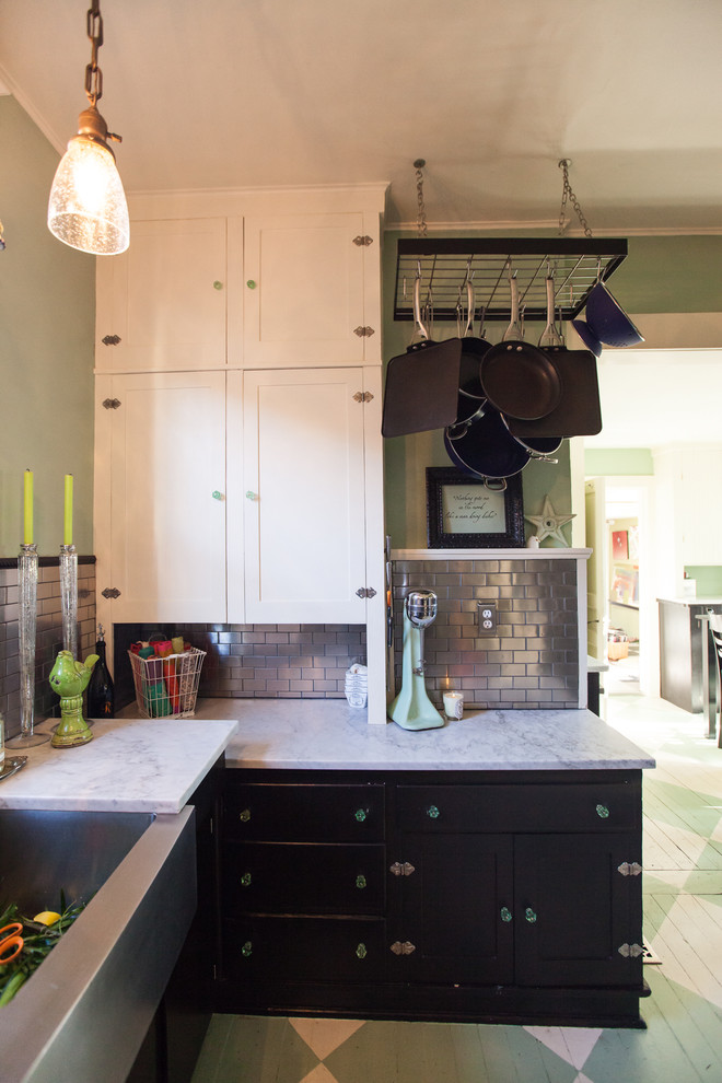 Photo of a small industrial u-shaped separate kitchen in Seattle with a farmhouse sink, shaker cabinets, marble benchtops, metallic splashback, stainless steel appliances, painted wood floors, no island, black cabinets, subway tile splashback, green floor and grey benchtop.