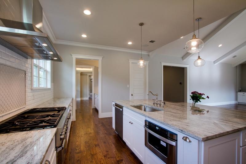 Large transitional u-shaped medium tone wood floor open concept kitchen photo in Dallas with a drop-in sink, flat-panel cabinets, white cabinets, granite countertops, white backsplash, subway tile backsplash, stainless steel appliances and an island