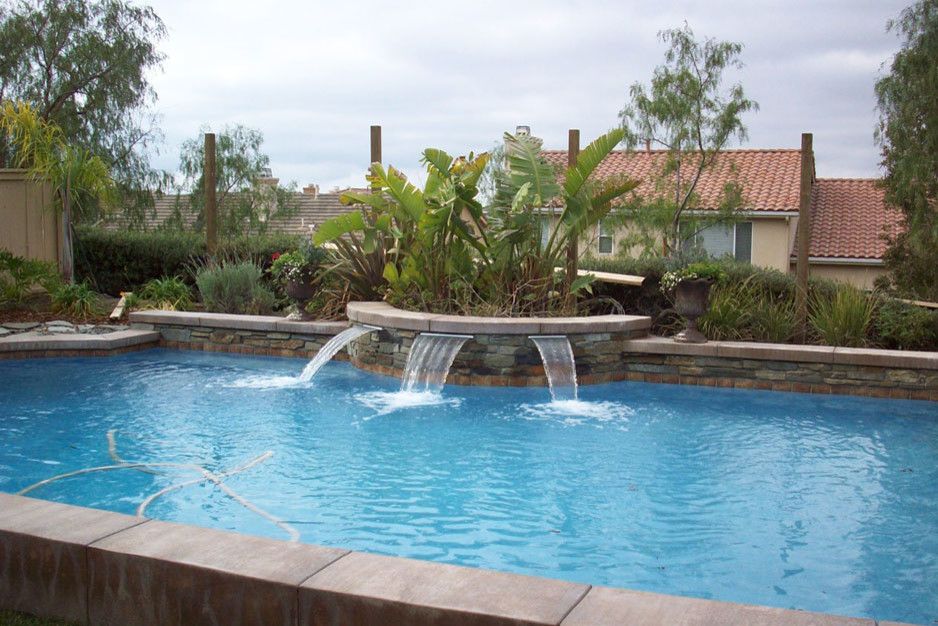 Photo of a mid-sized traditional backyard lap pool in Orange County with a water feature and concrete slab.