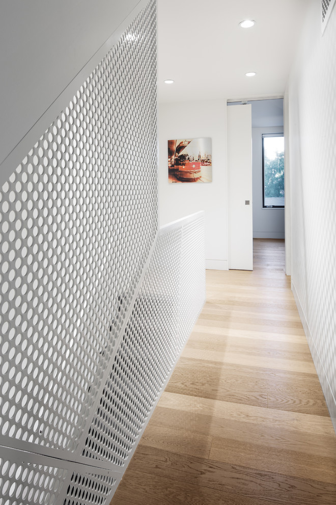 This is an example of a mid-sized contemporary hallway in Toronto with white walls and light hardwood floors.