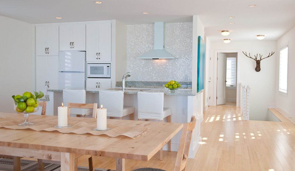 This is an example of an eat-in kitchen in Minneapolis with flat-panel cabinets, white cabinets, white splashback and white appliances.
