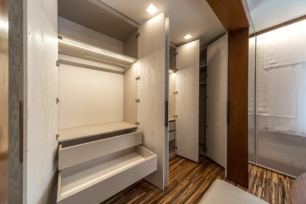 This is an example of a small asian gender-neutral built-in wardrobe in Saint Petersburg with flat-panel cabinets, light wood cabinets, medium hardwood floors and brown floor.