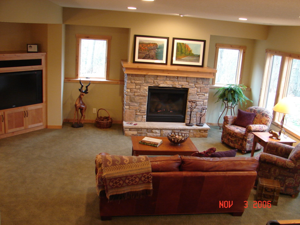 Photo of a mid-sized country open concept living room in Minneapolis with grey walls, carpet, a standard fireplace, a stone fireplace surround and a built-in media wall.