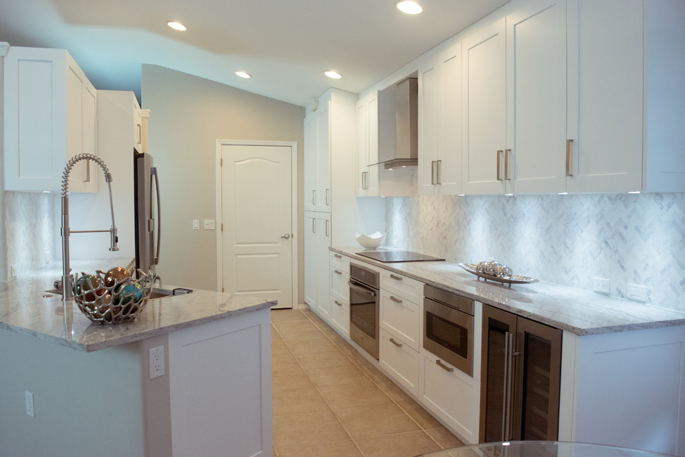 Eat-in kitchen - mid-sized transitional galley ceramic tile and beige floor eat-in kitchen idea in Miami with an undermount sink, shaker cabinets, white cabinets, granite countertops, gray backsplash, stone tile backsplash, stainless steel appliances and a peninsula