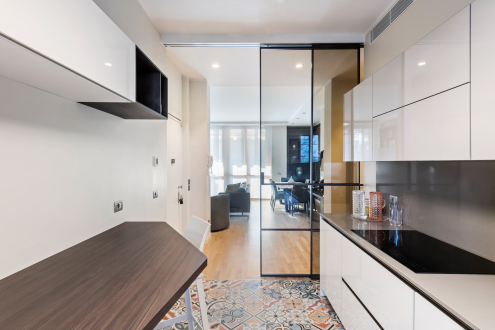 Mid-sized contemporary galley separate kitchen in Milan with a single-bowl sink, flat-panel cabinets, white cabinets, marble benchtops, beige splashback, marble splashback, white appliances, ceramic floors, multi-coloured floor, beige benchtop and recessed.