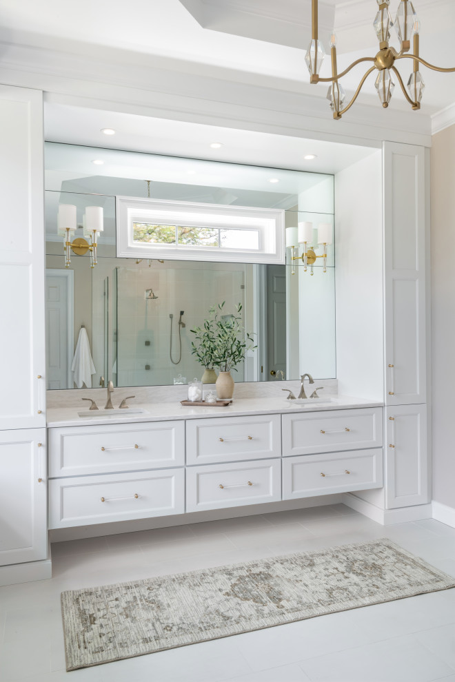 This is an example of a large transitional master bathroom in St Louis with a built-in vanity, shaker cabinets, white cabinets, a drop-in tub, a corner shower, white tile, porcelain tile, white walls, porcelain floors, an undermount sink, quartzite benchtops, yellow floor, an open shower, white benchtops, a shower seat, a double vanity and recessed.