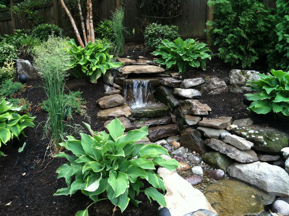 This is an example of a mid-sized asian backyard partial sun garden for spring in New York with natural stone pavers and with pond.