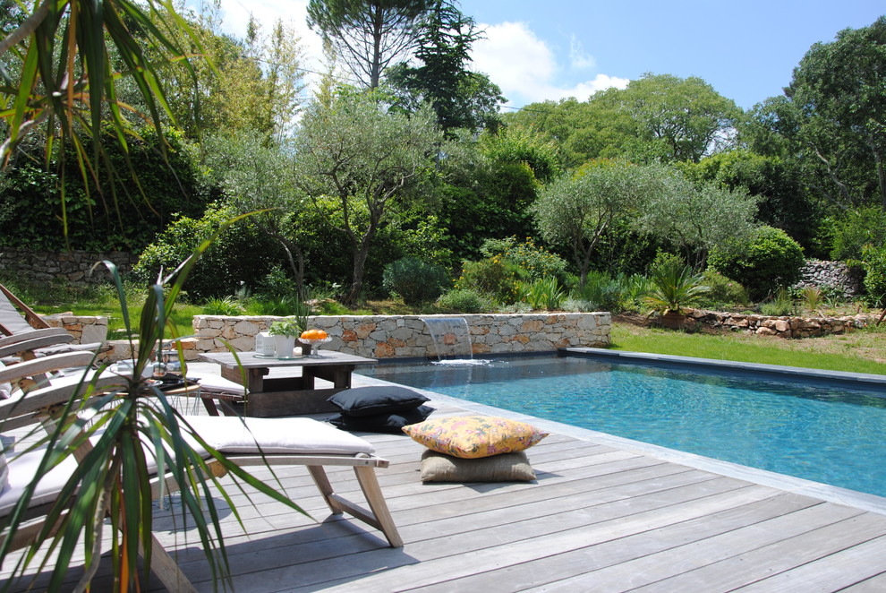 Contemporary backyard rectangular lap pool in Montpellier with a water feature and decking.