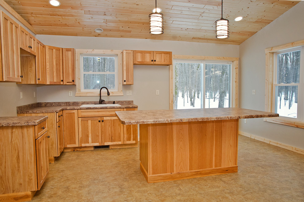 This is an example of a mid-sized country l-shaped open plan kitchen in Other with a drop-in sink, recessed-panel cabinets, light wood cabinets, laminate benchtops, linoleum floors, with island and brown floor.