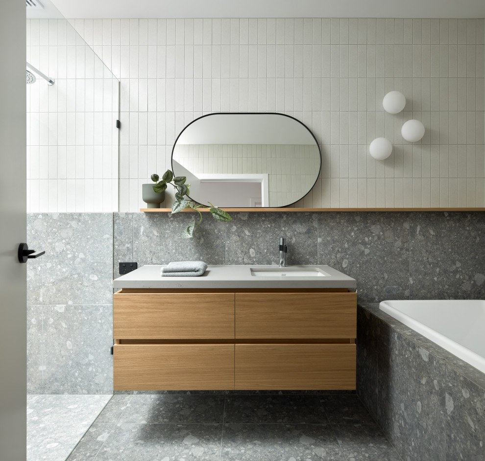 This is an example of a large contemporary bathroom in Melbourne with flat-panel cabinets, light wood cabinets, a drop-in tub, marble floors, solid surface benchtops, grey floor, a hinged shower door, grey benchtops, a single vanity and a floating vanity.