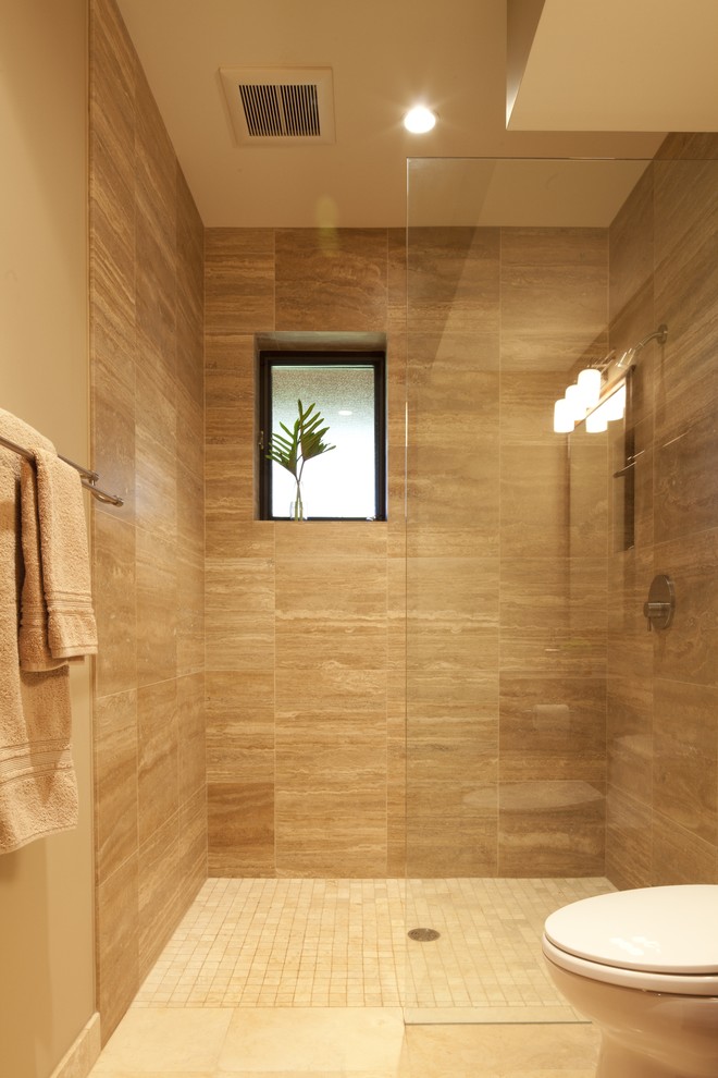 Inspiration for a mid-sized tropical bathroom in Seattle with recessed-panel cabinets, medium wood cabinets, a curbless shower, a two-piece toilet, beige tile, porcelain tile, beige walls, porcelain floors, an undermount sink, limestone benchtops, beige floor, an open shower and beige benchtops.