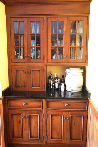 Mid-sized mountain style l-shaped medium tone wood floor eat-in kitchen photo in New York with an undermount sink, shaker cabinets, distressed cabinets, granite countertops, multicolored backsplash, stone slab backsplash, stainless steel appliances, yellow walls and an island