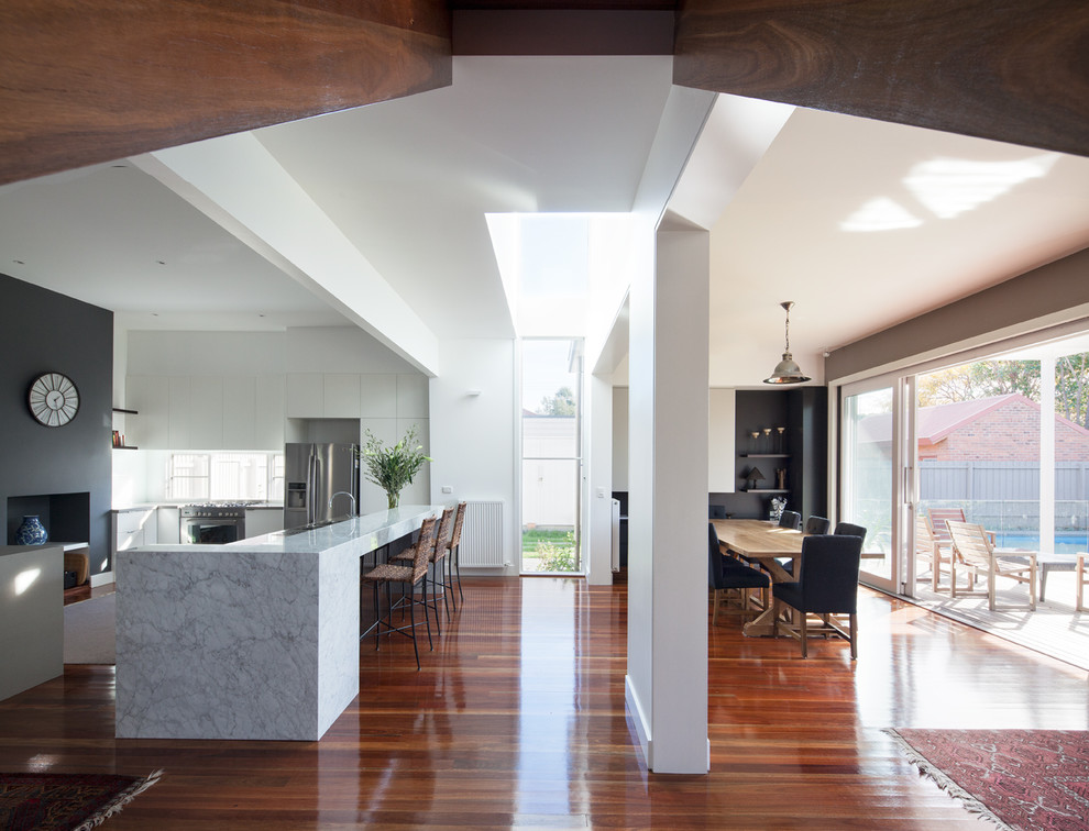 Inspiration for a large contemporary u-shaped eat-in kitchen in Melbourne with a double-bowl sink, flat-panel cabinets, white cabinets, marble benchtops, white splashback, glass sheet splashback, stainless steel appliances, medium hardwood floors and with island.