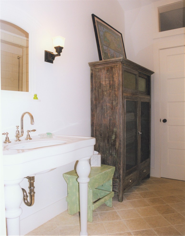 Photo of a mid-sized tropical 3/4 bathroom in San Francisco with an open shower, a one-piece toilet, white walls, an open shower, furniture-like cabinets, distressed cabinets, white tile, ceramic tile, travertine floors, a pedestal sink and beige floor.
