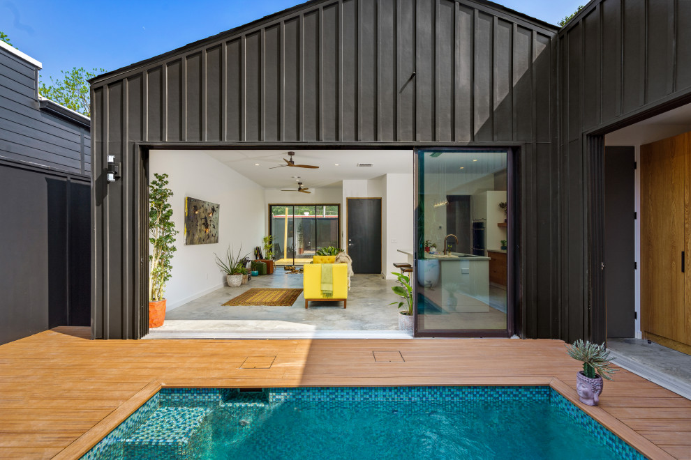 Small and black contemporary bungalow detached house in Houston with concrete fibreboard cladding, a pitched roof, a shingle roof, a black roof and board and batten cladding.