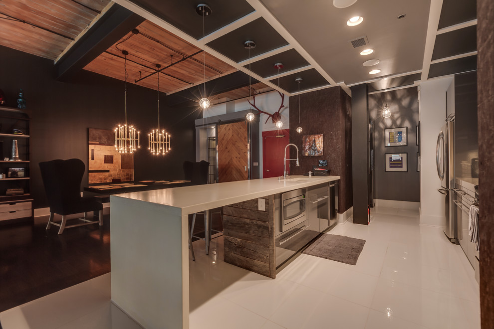 This is an example of a large industrial single-wall open plan kitchen in Charlotte with an undermount sink, flat-panel cabinets, grey cabinets, quartz benchtops, metallic splashback, matchstick tile splashback, stainless steel appliances, linoleum floors, with island and white floor.