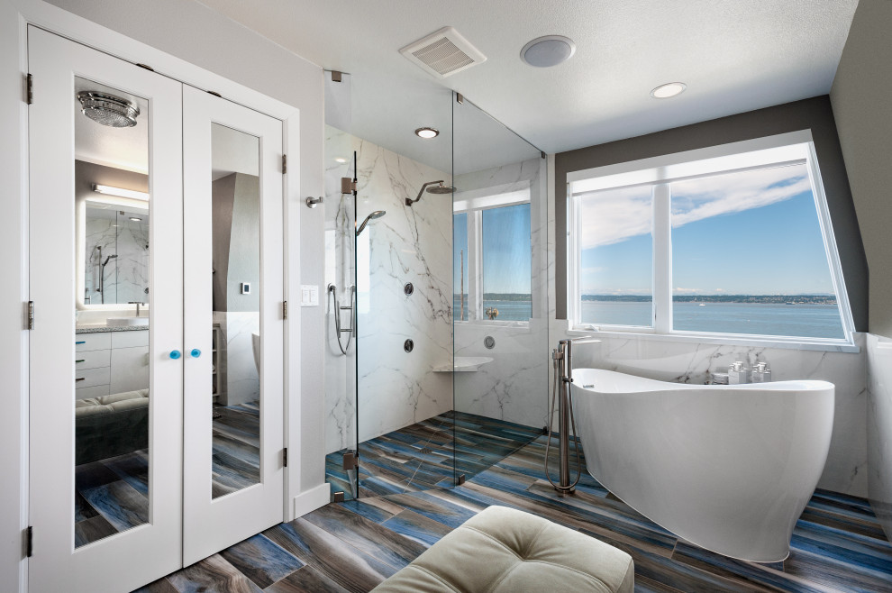 Пример оригинального дизайна: большая главная ванная комната в современном стиле с плоскими фасадами, белыми фасадами, отдельно стоящей ванной, душем без бортиков, раздельным унитазом, белой плиткой, плиткой из листового камня, серыми стенами, полом из плитки под дерево, настольной раковиной, столешницей из искусственного кварца, синим полом, душем с распашными дверями, бежевой столешницей, сиденьем для душа, тумбой под две раковины и встроенной тумбой
