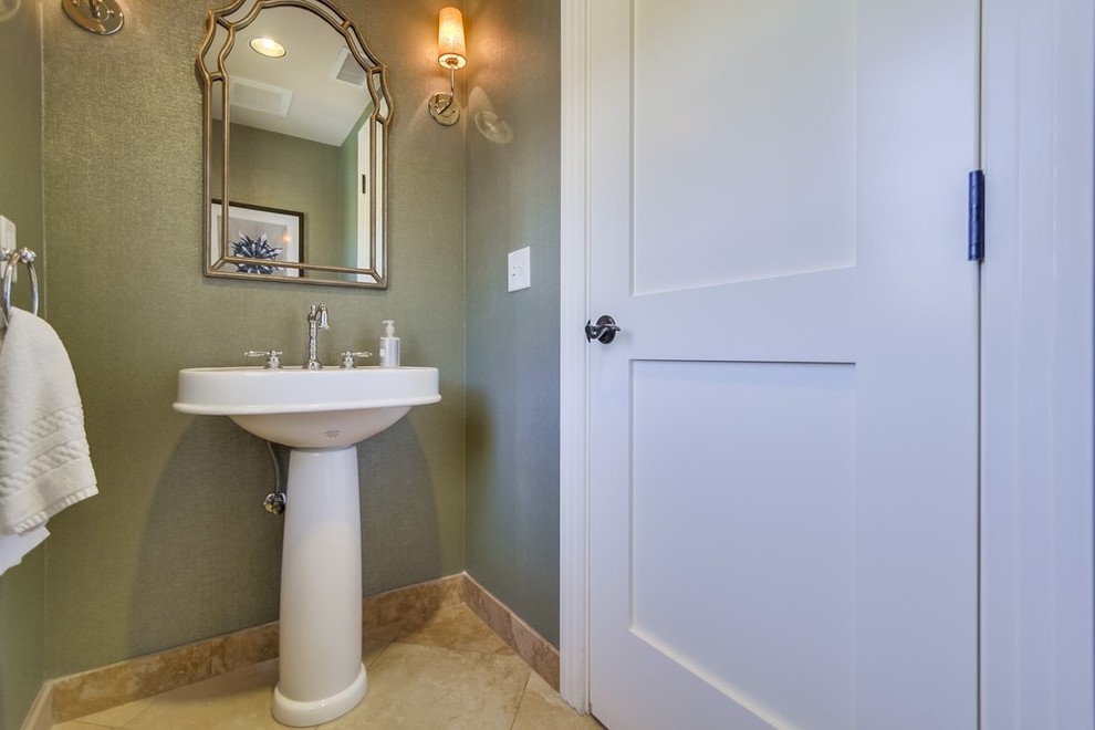 Inspiration for a transitional powder room in Los Angeles with a pedestal sink, green walls and travertine floors.