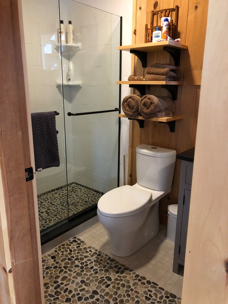 Inspiration for an arts and crafts bathroom in Portland Maine with shaker cabinets, blue cabinets, a curbless shower, a one-piece toilet, white tile, ceramic tile, multi-coloured walls, ceramic floors, granite benchtops, multi-coloured floor, a sliding shower screen and black benchtops.