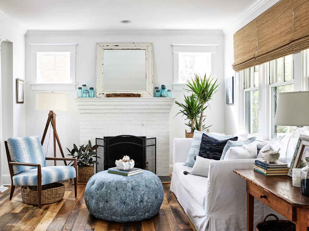 Inspiration for a beach style living room in DC Metro with white walls, medium hardwood floors, a standard fireplace, a brick fireplace surround and brown floor.