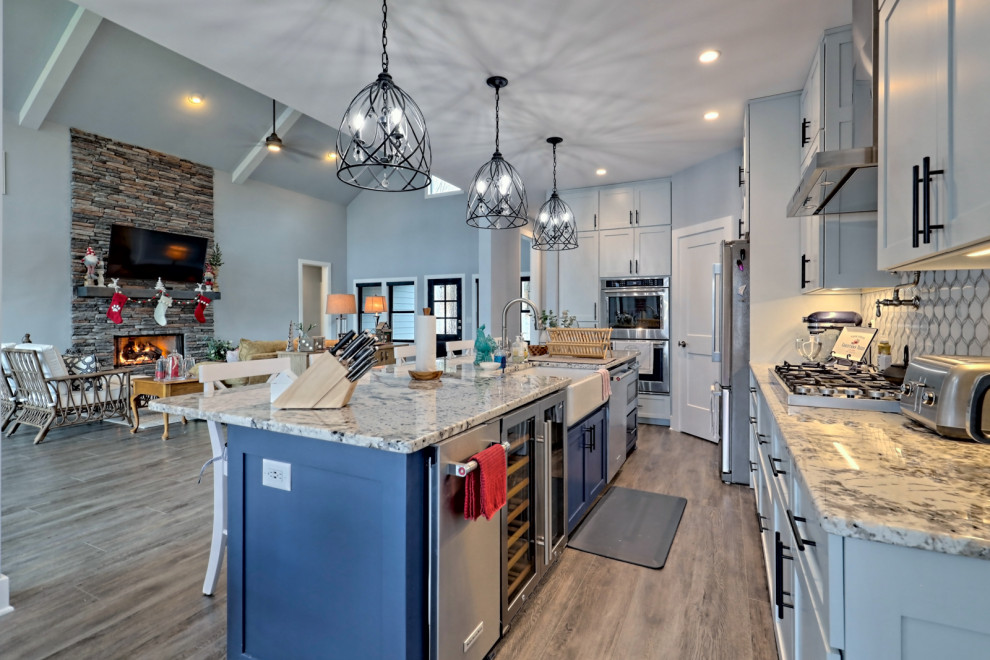 Design ideas for a large transitional l-shaped open plan kitchen in Atlanta with a farmhouse sink, shaker cabinets, grey cabinets, granite benchtops, white splashback, glass tile splashback, stainless steel appliances, vinyl floors, with island, grey floor and multi-coloured benchtop.