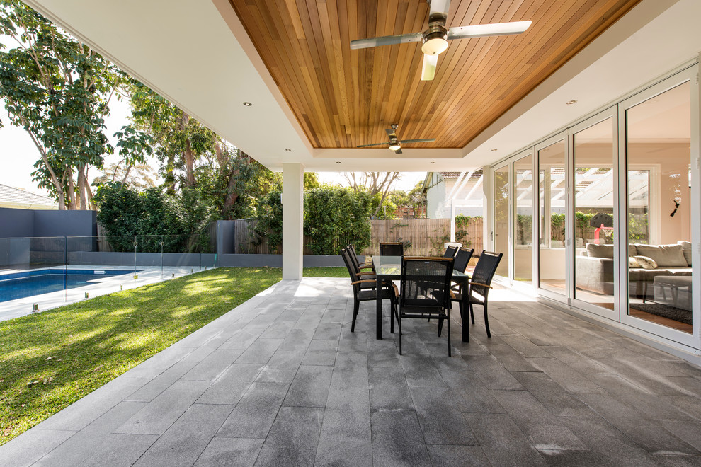This is an example of a mid-sized contemporary backyard deck in Perth with a roof extension.