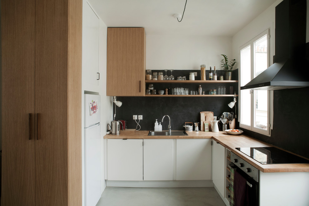 Inspiration for a contemporary u-shaped separate kitchen in Paris with a drop-in sink, flat-panel cabinets, white cabinets, wood benchtops, black splashback, white appliances, concrete floors, no island, grey floor and beige benchtop.