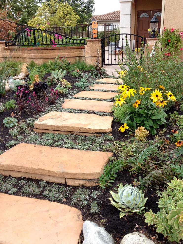 Inspiration for a mid-sized mediterranean front yard full sun formal garden for spring in Los Angeles with natural stone pavers and a garden path.
