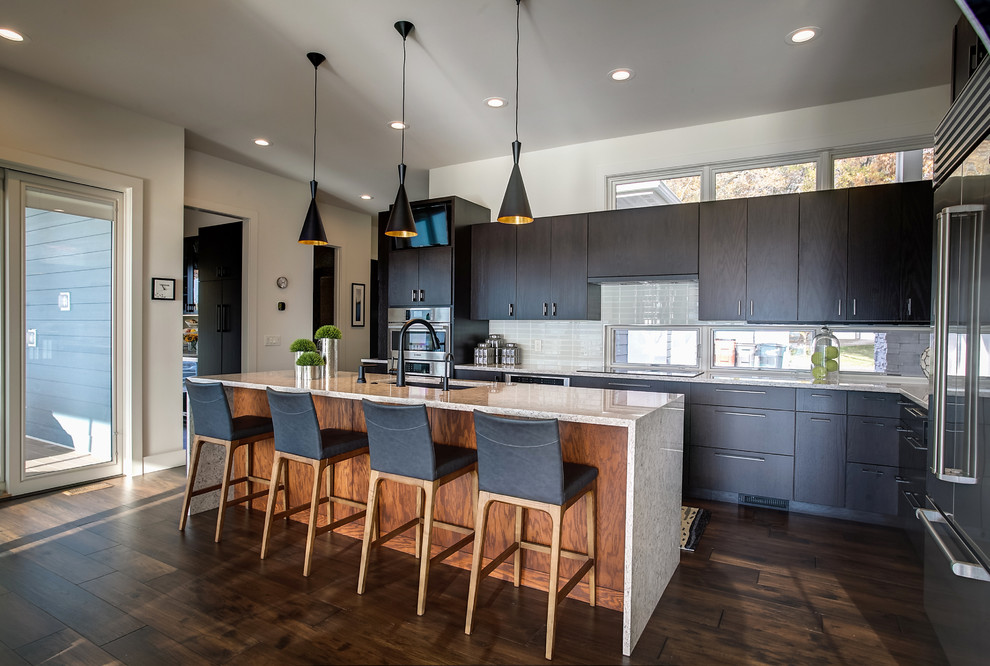 Large contemporary l-shaped eat-in kitchen in Grand Rapids with an undermount sink, flat-panel cabinets, dark wood cabinets, quartz benchtops, grey splashback, glass tile splashback, stainless steel appliances, medium hardwood floors and with island.