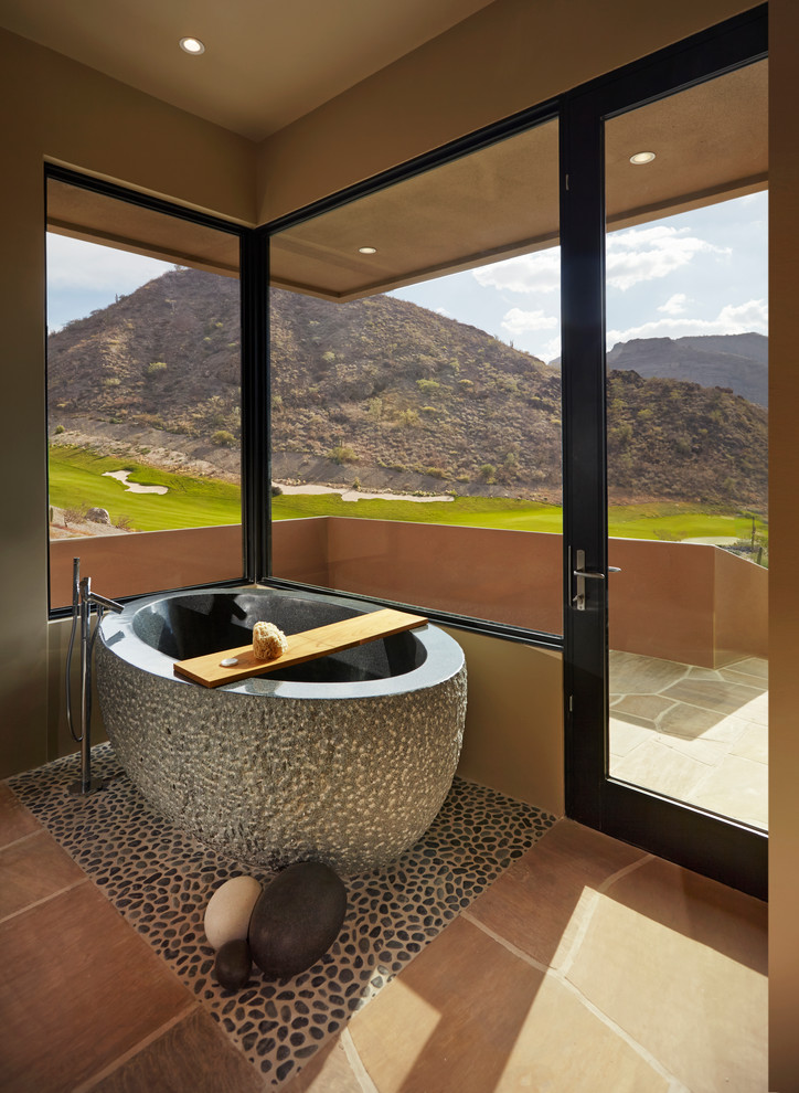 Photo of a large master bathroom in Other with a freestanding tub, limestone floors, brown floor and brown walls.