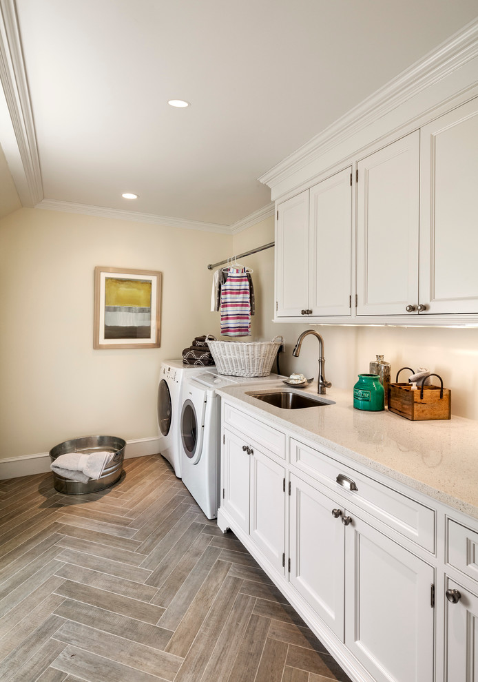 Inspiration for a large traditional galley dedicated laundry room in Other with white cabinets, a side-by-side washer and dryer, an undermount sink, recessed-panel cabinets, solid surface benchtops, beige walls and porcelain floors.